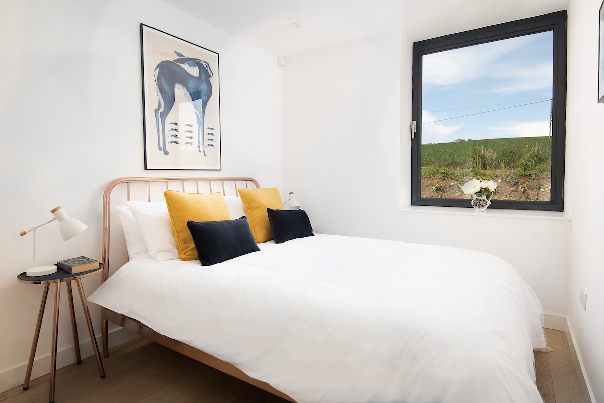 7 The Bay, Coldingham - bedroom one has a modern copper-framed king size bed dressed in crisp white linen