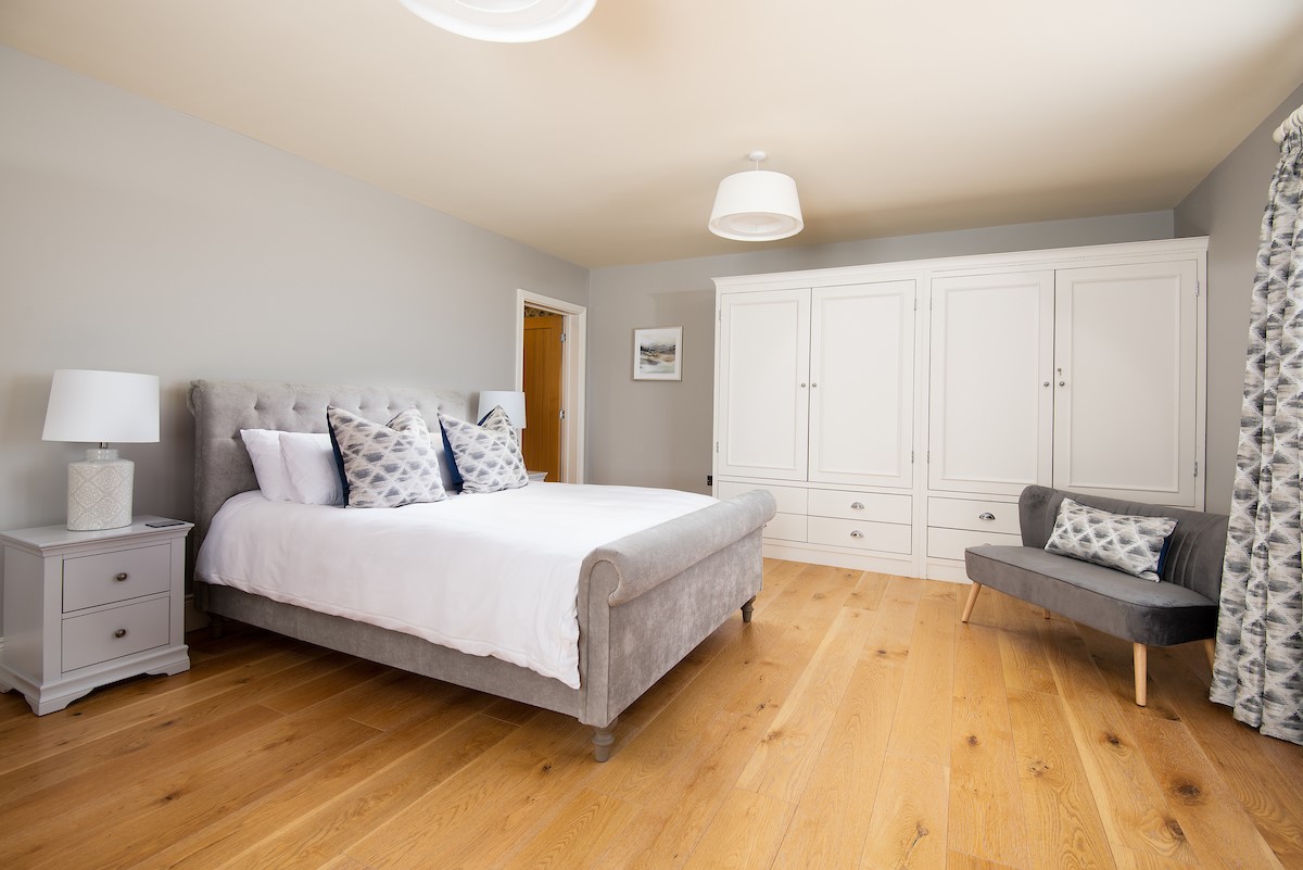 Bracken Lodge - bedroom one with a plush king size bed with ample storage and sofa seat for two