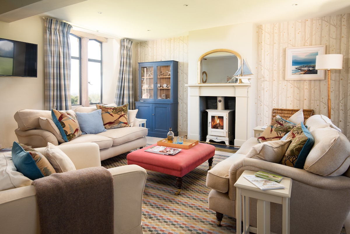 Lindisfarne View - sitting room with deep comfortable sofas set around the wood burning stove