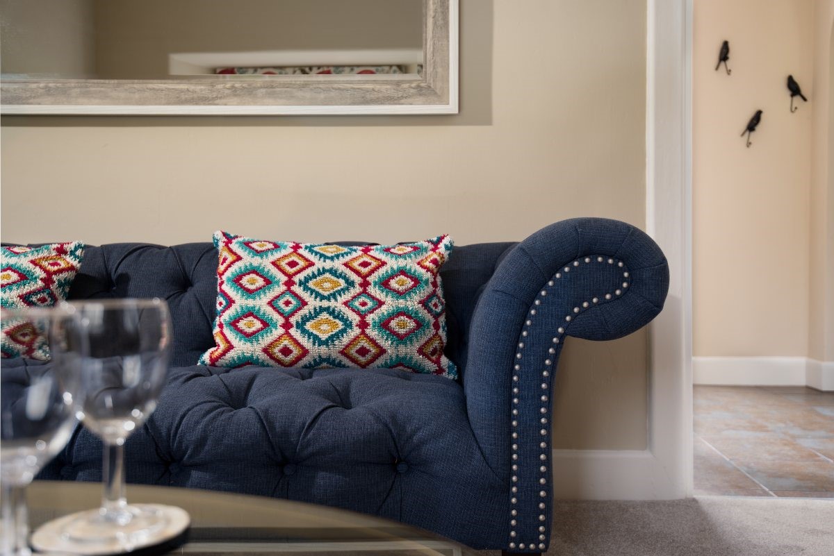 Birch Cottage - vibrant cushions pop against the inky blue Chesterfield sofa
