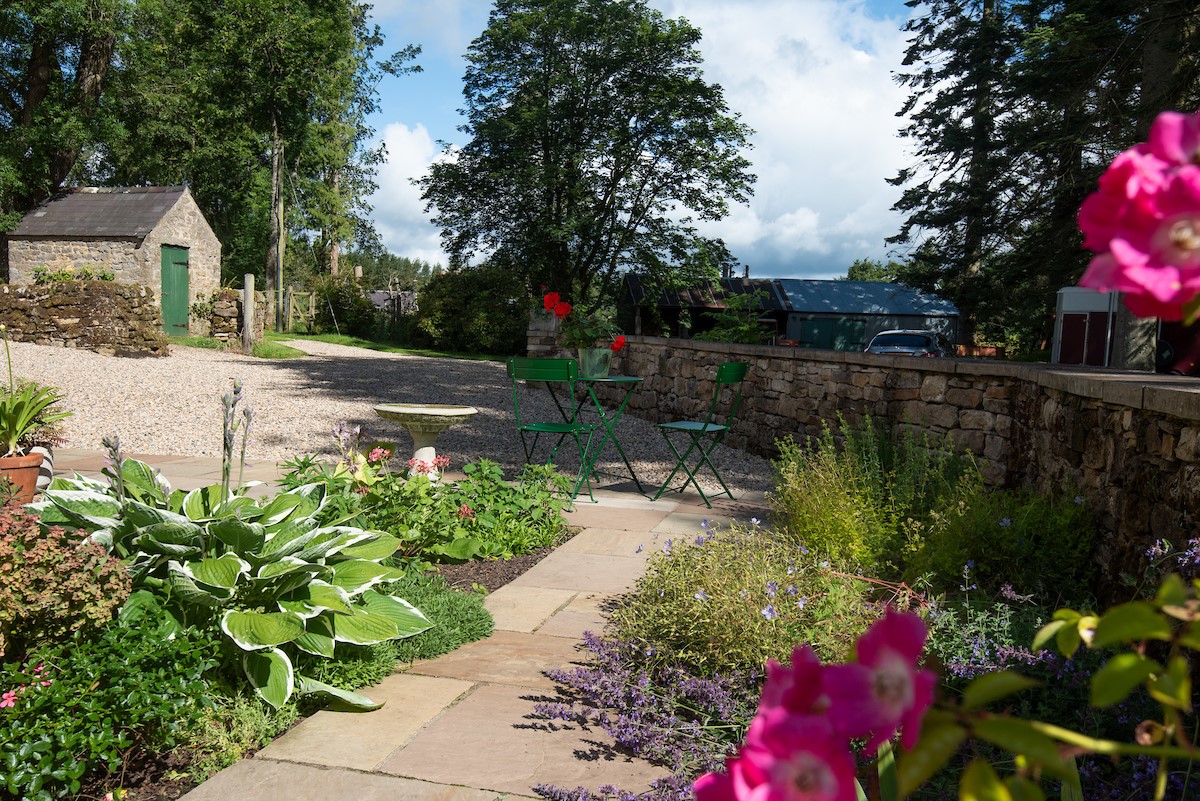Birks Stable Cottage - bistro dining set on the patio surrounded by pretty herbaceous borders