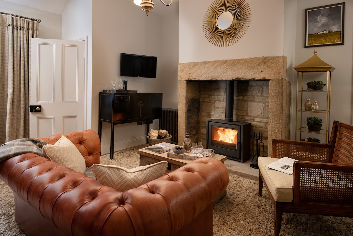 The Lodge, Lesbury - small chesterfield sofa and a wood burning stove