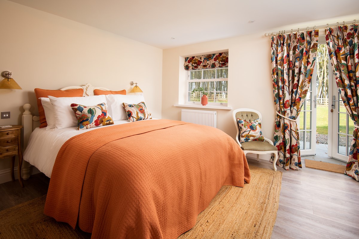 Greenhead Cottage - bedroom one sits on the ground floor with king size bed and French doors leading out to the garden