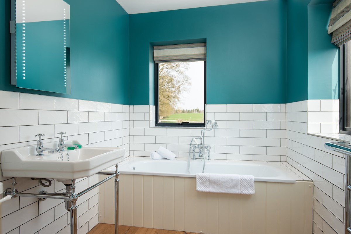 Lakeside Cottage - Alice - the family bathroom features a bath with handheld mixer and subway-style tiling throughout