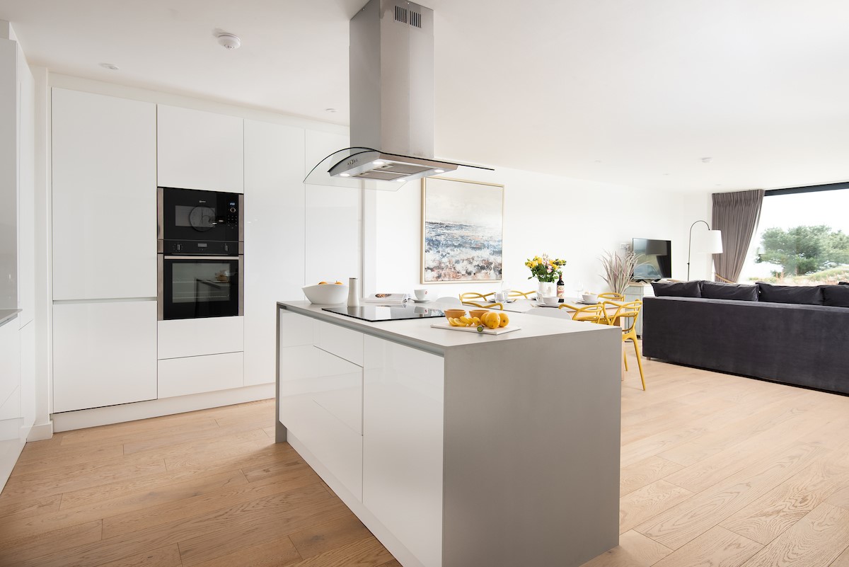 1 The Bay, Coldingham - clean and elegant kitchen with white high gloss cabinetry and an induction hob housed on the central island