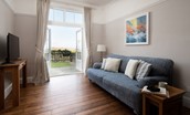 Sandsend - snug area beside the kitchen with three-seater sofa, Smart TV and patio doors leading out to the garden