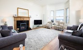 East Bay Beach House - sitting room with sofas, armchairs, gas fire and large bay window with sea views