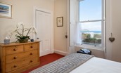 East Bay Beach House - bedroom one with double bed, chest of drawers and sea views