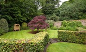 Stable Cottage, Glanton Pyke - the lawned garden to the rear of the property featuring a swing bench for guest to sit and relax