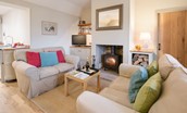 Barley Hill Cottage - the living area with wood burning stove with door leading to bedroom one
