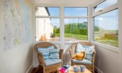 Beachcomber Cottage - the access porch with wicker chairs and map of local area