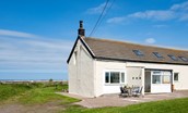 Beachcomber Cottage - the exterior of the cottage with access door and Goswick beach in the background