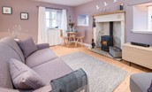 Braemar - sitting room with sofa, dining space and wood burning stove