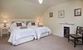 Byreman's Cottage - bedroom three with zip and link beds, bedside tables and decorative fireplace