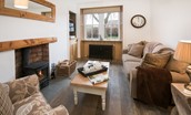 Chestnut Cottage - sitting room area with wood burning stove, sofa, armchair and TV