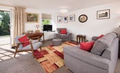 Coldstream Coach House - sitting room with sofa, TV, two armchairs and door leading to the patio