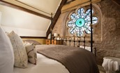 Lindisfarne View - bedroom two with cast iron bedstead and stunning stained glass window detailing