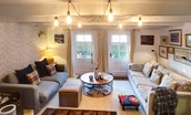 Nook End - sitting room with three-seater sofa and a tow seater sofa. Large bi-fold doors lead out to the garden