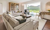 Granary - sitting room with large sofas, armchair and bi-fold doors leading to garden with view of Eildon hills