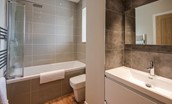 Granary - bedroom two en suite bathroom with bath and shower over, WC and basin