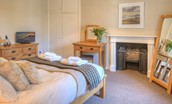 Grove House - bedroom one with king size bed, dressing table, chest of drawers and decorative fireplace
