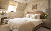 Bughtrig Cottage - bedroom one features a king size bed draped in crisp white linen