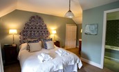 The Boathouse - bedroom four with large patterned headboard and en suite bathroom