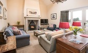 Crookhouse Mill - open-plan living area with wood burning stove, sofas, armchairs and French doors leading outside