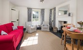 Garden Cottage - open-plan living area with sofa, armchairs, wood burning stove and dining space for four guests
