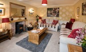 Dryburgh Stirling One - sitting room with sofas, wood burning stove, coffee table and red accents