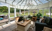 Dryburgh Stirling Two - conservatory with sofas, coffee table and doors leading into the garden