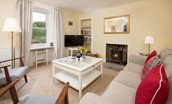 Gardener's Cottage, Elliston - sitting room with wood burning stove, TV, sofa and two armchairs
