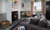 Calder Cottage - sitting room with wood burning stove, sofa, armchair and sea views