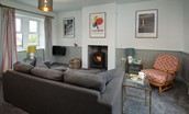 Calder Cottage - sitting room with sofa, wood burning stove and framed prints