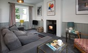 Calder Cottage - sitting room with sofa, wood burning stove and views to the front of the cottage