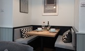 Calder Cottage - dining area with bench seating and monochrome cushions and prints