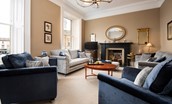 The Linen House - a light-filled drawing room with original slate fireplace, generous sofas and fine antiques