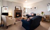 The Bothy at Cheswick - sitting room with comfortable seating, wood burner and dining area in the open-plan living space