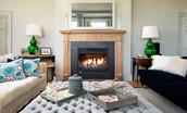 Honeystone House - large open fire in the drawing room with sumptuous seating and footstool