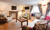 The Craftsman's Cottage - spacious sitting room with ample seating for guests and a decorative stone mantelpiece