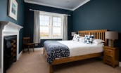 Sandsend - bedroom one with king size bed, wardrobe, chest of drawers, decorative fireplace and views towards Bamburgh Castle