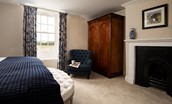 Brockmill Farmhouse - bedroom two with decorative feature fireplace and large south-facing sash window with original shutters overlooking the garden