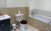 Wark Farmhouse - bedroom four en suite bathroom with bath, handheld shower attachment, WC and basin