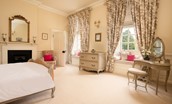 Eslington East Wing - bedroom three with king size bed, dressing table with mirror and stool, and decorative fireplace