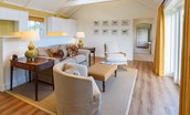 Fenton Lodge - sitting room with side tables, sofa and armchairs positioned to enjoy the view out of the French doors