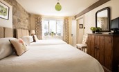 Anvil Cottage - bedroom two with queen size beds and exposed stone wall