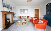 Sea Breeze - cosy sitting room with comfortable seating, coffee table, dresser and wood burner
