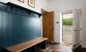 The Old Vicarage - bench seating with coat hooks and shoe storage in the utility/boot room, the access door leads out to the enclosed courtyard
