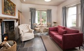 Park End - airy sitting room with sofa for two and single armchair in front of the wood burner