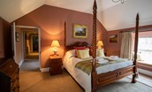 The Boathouse - bedroom two with four-poster bed and first floor hallway leading to other bedrooms